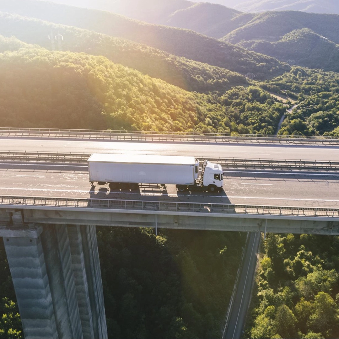 Camiones llevando contenedores de carga por la ruta, desde atrás